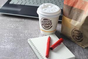 WASHINGTON - USA - August 17, 2024 - A close-up of a Burger King coffee cup, with a laptop and a paper bag in the background. photo