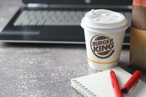 WASHINGTON - USA - August 17, 2024 - A close-up of a Burger King coffee cup, with a laptop and a paper bag in the background. photo