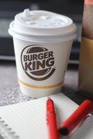 WASHINGTON - USA - August 17, 2024 - A close-up of a Burger King coffee cup, with a laptop and a paper bag in the background. photo