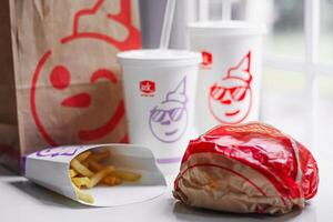 WASHINGTON, USA - August 08, 2024 - A table setting featuring a fast food order from Jack in the Box. The meal includes two white styrofoam cups with red lids and straws, and a wrapped burger. photo