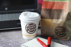 WASHINGTON - USA - August 17, 2024 - A close-up of a Burger King coffee cup, with a laptop and a paper bag in the background. photo