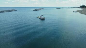 A boat floating near a calm shoreline on a sunny day. A serene image of a boat floating in calm waters near the shore on a sunny day. video