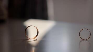 Close-up of a wedding ring in soft sunlight. A close-up shot of a simple wedding ring illuminated by soft sunlight, casting a delicate shadow on the table. video