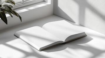 Open blank book in a sunlit corner by a window, with shadows cast from natural light and nearby plants photo