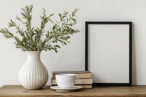 Minimalist home decor with a vase of olive branches, a framed blank picture, and a cup on a wooden table photo