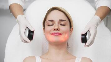 A cosmetologist performs LED light therapy for facial rejuvenation. This non-invasive treatment improves skin elasticity, reduces aging signs, and enhances overall skin radiance video
