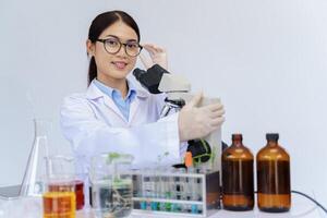 Woman scientist looking through a microscope in a laboratory. Scientist lab assistant with medical gown doing some research, medicine science concept. photo