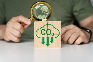 Hand assemble CO2 reducing icon on wooden block cube on nature for decrease CO2 photo