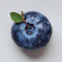 a blueberry with a leaf on it on a white surface photo