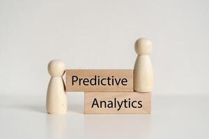 Two wooden figures are stacked on top of each other with the word predictive analytics photo
