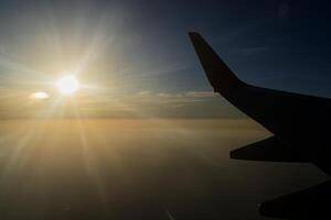 View from airplane on the aircraft white wing flying over desert landscape in sunny morning. Air travel and transportation concept. photo