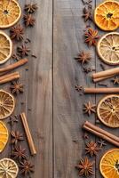 vertical top view border frame of cinnamon sticks, dried oranges and star anise on wooden background flat lay template with copy space photo
