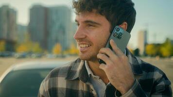 Smiling guy handsome 30s Caucasian man driver talk mobile phone with auto car background on parking happy male successful businessman calling smartphone friendly conversation in city urban lifestyle photo