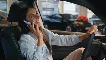 contento caucásico exitoso mujer de negocios hablando móvil teléfono llamada simpático conversacion alegre mujer sentar en nuevo coche en automóvil tienda alquilar Servicio alquiler comprando auto lujo vehículo hablar teléfono inteligente foto