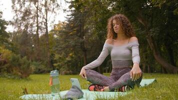 contento juguetón mujer hombre de influencia al aire libre en parque grabar teléfono Deportes aptitud Blog ajuste vlog en línea niña ondulación Hola distante Internet entrenador comienzo deporte rutina de ejercicio yoga en estera giro cabeza a lado foto
