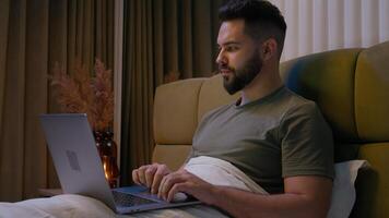 Caucasian man bed remote working laptop typing home computer gadget businessman entrepreneur employee male freelancer desk internet programmer browsing user networking technology business bedroom guy photo