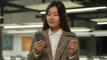 asiático mujer de negocios chino dama coreano negocio mujer niña hembra empleador japonés ejecutivo en oficina utilizar móvil teléfono compras teléfono inteligente aplicación contento crédito tarjeta banco en línea comprando pago éxito foto