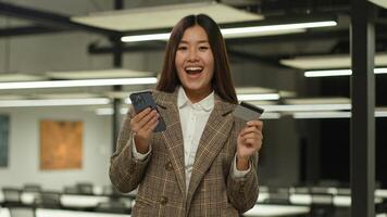 asiático mujer de negocios chino dama coreano negocio mujer niña hembra empleador japonés ejecutivo en oficina utilizar móvil teléfono compras teléfono inteligente aplicación contento crédito tarjeta banco en línea comprando pago éxito foto