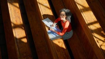 Top view from above woman girl student female study at table writing studying learning write learn course copybook in empty sunny shadows class college university auditorium looking at camera smiling photo