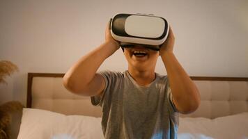 Funny enthusiastic smiling child kid boy schoolboy play game using innovative digital VR goggles playing online 3d AR technology in metaverse world wearing virtual reality glasses at home on bed photo