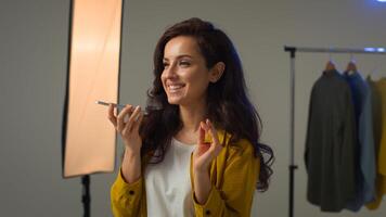 Happy positive Caucasian woman lady female blogger typing mobile phone cellphone recording voice message audio voicemail social network blog. Model influencer girl smiling talking call photo studio
