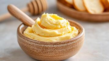 Fresh honey butter in a ceramic dish with a wooden knife on a rustic market stall background photo