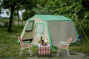 selective focus of Vintage drip coffee set and baguette on a table in front of a camping tent in the forest in the morning, soft focus. photo