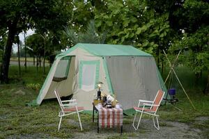 selective focus of Vintage drip coffee set and baguette on a table in front of a camping tent in the forest in the morning, soft focus. photo