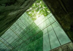 Eco-friendly building in modern city. Sustainable glass office structure with integrated greenery to reduce heat and carbon dioxide. Corporate architecture. Reducing CO2 emissions. Green environment. photo