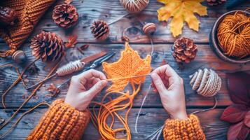 Hands crafting knitted autumn leaf surrounded by autumn-themed decorations photo