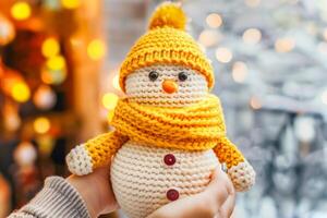 Female hands holding handmade knitted snowman wearing yellow hat and scarf, symbolizing sustainable and eco-friendly Christmas decor. Concept of green Christmas, DIY crafts, and festive creativity photo
