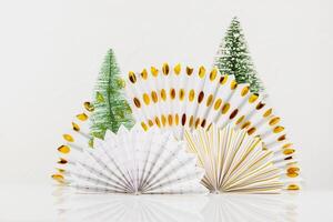 Holiday composition with paper fans and new year trees on white background photo