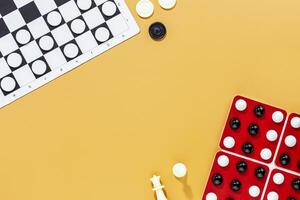 Various board games with chess pieces and checkers on orange background photo
