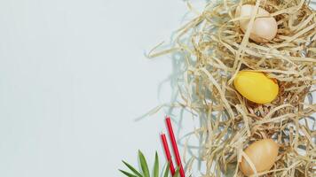 Colored eggs on shredded paper, candles and palm leaf with copy space photo