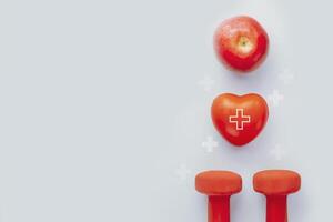 Red heart, apple and dumbbells on blue background with copy space photo