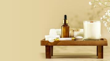 Serum, face roller, towel and candle on wooden podium with copy space photo