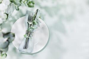 Table settings on blue background with eucalyptus leaves and copy space photo