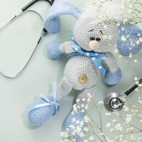 Knitted toy rabbit with a stethoscope, white flowers photo