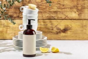 Bottle with dish detergent with clean plates and cups with copy space photo