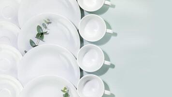 Empty dishes and cups with eucalyptus twigs on blue background with copy space photo