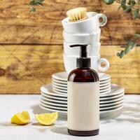 Bottle with dish detergent with clean plates and cups photo