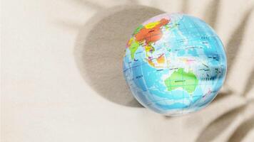 Globe of the planet Earth on sandy beach background with palm leaf shadow photo