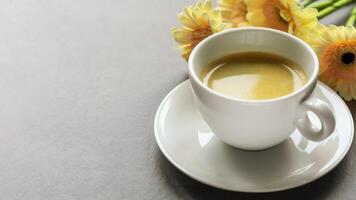 Cup of espresso with gerberas on grey marble background with copy space photo