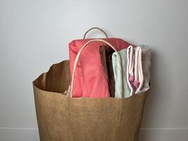 A brown paper bag overflowing with old clothing items, ready for donation or recycling. photo