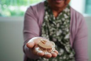 Asian senior woman patient using hearing aid in ear to reduce hearing loss problem. photo