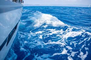 Yacht sailing in an open sea. Close-up view of side of the boat. Clear sky after the rain, waves and water splashes. High quality photo