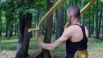 Side view from the back without a face, a Caucasian man goes in for sports outdoors, shaking the muscles of his arms and back video