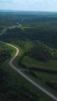 Panorama of country road with green forest. Clip. Top view of road and forest landscape on background of horizon with sky. Beautiful view of highway passing through forest area in summer video
