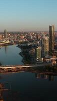 Top view of modern city with river with horizon at dawn. Stock footage. Beautiful city with high-rises and reflection in river at dawn. Panorama of modern city on background horizon in rays of dawn video
