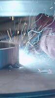 Welder in gloves holds welding with flying sparks. Creative. Sparks while working with welding and steel structures. Welding tube with sparks from metal structure video